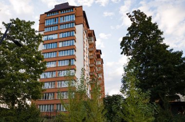 Gün ışığı solmaya başladığında yumuşak, bulutlu bir gökyüzü altında çağdaş mimari sergilenen canlı ağaçlarla çevrili uzun konut yapısı gururla duruyor..