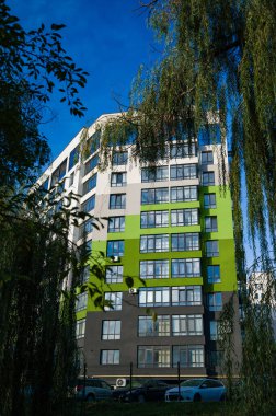 Dinamik bir şehir manzarasında, çarpıcı bir bina, doğanın güzelliği ile çağdaş tasarımı harmanlayarak uzun süre ayakta kalır. Güneş ışığı, açık mavi gökyüzüne karşı rengarenk yüzü aydınlatır..