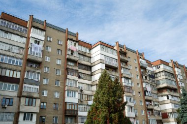 Parlak ışıklı konut binaları mavi gökyüzüne karşı yükseliyor, çamaşırhaneler asılarak süslenen balkonlar, şehir sakinlerinin şehir yaşamının ortasındaki günlük rutinlerini yansıtıyor..