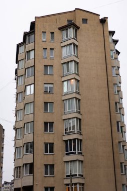 Çarpıcı bir konut yapısı, mahallenin çağdaş mimari tarzını yansıtan geniş pencereli bulutlu bir gökyüzüne karşı dimdik ayakta duruyor..