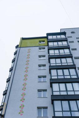 Canlı çiçek freskleri, yukarıdaki gri gökyüzü ile çelişen ve şehir manzarasının çekiciliğini ve karakterini artıran gösterişli bir apartmana cazibe katar..