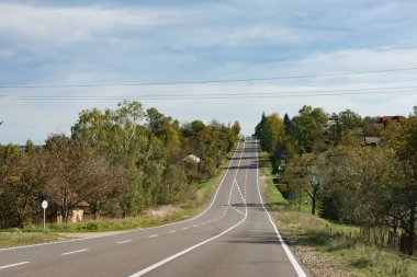Dönek yol kıvrımlı tepeler boyunca uzanır ağaçlarla süslenir, canlı sonbahar renkleri sergiler, kırsal bir manzara yaratır keşifleri davet eder..