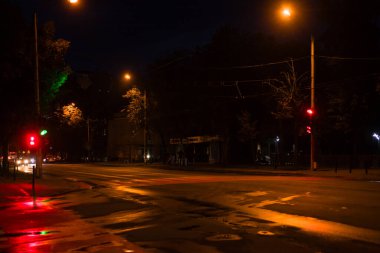 Sokak lambaları ve trafik ışıklarının yumuşak parıltısı gece sakin bir kavşakta bir ortam yaratıyor ve az sayıda araba geçiyor..