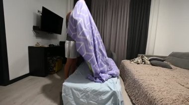 Yumuşak bir battaniyeyi açarak, modern dekorasyon ve sıcak aydınlatmayla süslenmiş şık bir oturma odasına yerleşmeye hazırlanıyor..