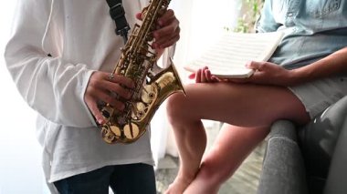 Genç bir saksafoncu enstrümanını dikkatle tutar ve müzik notalarında onlara rehberlik eder. Yaratıcılık ve öğrenmeyle dolu barışçıl bir atmosfer yaratır..