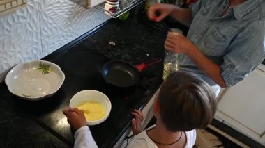Sıcak ve davetkar bir mutfakta, bir anne çocuğuyla keyifli bir yemek pişirme deneyimini paylaşır. Birlikte, aşçılık yaratıcılığı üzerine bir bağ kurmak için malzemeleri coşkuyla karıştırıyorlar..