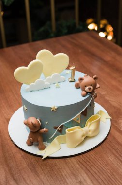 Hoş bir ilk doğum günü pastasında sevimli oyuncak ayılar, pastel kalpler ve büyüleyici bir kiraz kuşu bulunur. Açık mavi krema ve ince yıldız aksanları tatlı ve tuhaf bir tasarım yaratır..