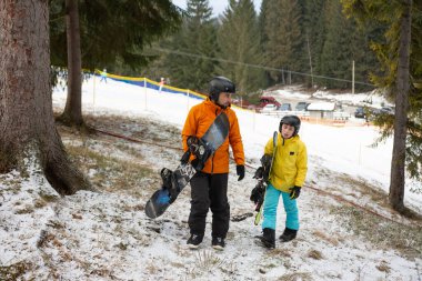 Bir ebeveyn ve çocuk olarak heyecan havayı heyecan verici bir şekilde dolduruyor. Karlı bir dağ yamacında kar kayağı günü. Canlı ağaçlar ve kış harikalar diyarı.