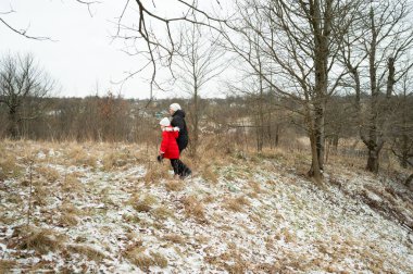 Huzurlu bir kış gününün tadını çıkaran bir adam ve bir çocuk çıplak ağaçlarla çevrili karlı bir tarlada geziniyor ve ayağının altındaki yumuşak bir buz örtüsü keşif anlarını paylaşıyor..