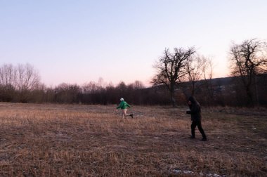 Çocuklar alacakaranlıkta uçsuz bucaksız bir tarlada özgürce koşar, ferahlatıcı akşam havasının ve doğanın güzelliğinin tadını çıkarırlar, solan ışığa karşı silueti olan ağaçlarla birlikte..