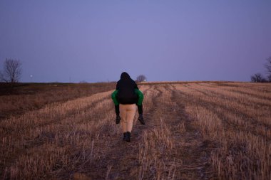 İki arkadaş engin, hasat edilmiş bir tarlada alacakaranlıkta keyifle yürürler, biri diğerinin sırtına biner güneş arka planda batarken..