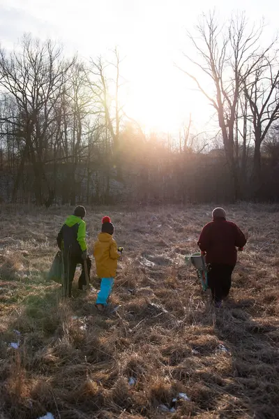 Dostlar ve aile sakin bir kış çayırında yürür, güneş batarken yakacak odun toplar, buzlu çimenler ve çıplak ağaçlar üzerinde sıcak bir parıltı saçar..
