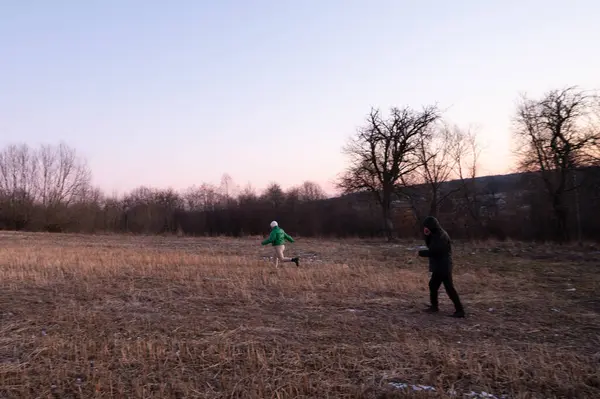 Çocuklar alacakaranlıkta uçsuz bucaksız bir tarlada özgürce koşar, ferahlatıcı akşam havasının ve doğanın güzelliğinin tadını çıkarırlar, solan ışığa karşı silueti olan ağaçlarla birlikte..