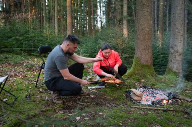 Bereketli bir ormanda, bir çift açık ateşin üzerinde yemek hazırlar, doğanın seslerine dalarken altın saat onların açık hava yemek maceralarına sıcak bir ışık saçar.