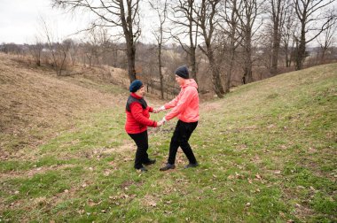 İki arkadaş güzel bir sonbahar gününde, doğanın güzellikleriyle çevrili sakin bir parkta birlikte dans ederek, keyifli bir anı paylaşıyorlar. Gülüşleri serin ortamda sıcaklık saçıyor..