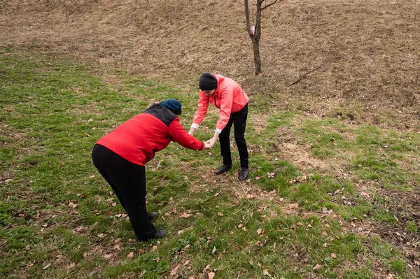 Bereketli yeşil bir alanda, iki işçi eğilip çevreyi temizlemek için güçlerini birleştirirken, toplum ruhu ve çevresel bakımı somutlaştırarak yavruları kavrıyor..
