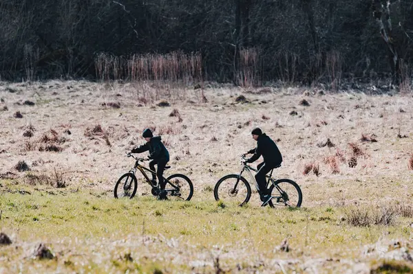 Dağ bisikletleriyle gezen iki birey sakin bir arazide, doğanın huzuru içinde huzurlu bir doğa deneyimi yaşıyor. Manzara sakin ve davetkar..