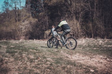 Güneşli bir günde bir baba ve oğulun birlikte bisiklet sürdüğü yürek ısıtan bir sahne. Huzurlu bir ormanda at sürüyorlar, dışarıda güzel vakit geçiriyorlar..
