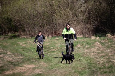 Baba ve oğul tarlada bisiklet sürüyor. Doğada aileyle aktif eğlence..