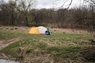 Dostlar, serin ve bulutlu bir günde, doğanın sükunetiyle çevrili iken nehir kenarında canlı bir çadırda toplanır, hikayeler ve kahkahalar paylaşırlar..