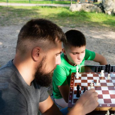 Sakallı bir adam ve genç bir çocuk dikkatle parktaki portatif bir satranç tahtasına kurulmuş bir satranç maçına odaklanırlar. Odaklandıkları nokta onların konsantrasyonu ve oyunu.