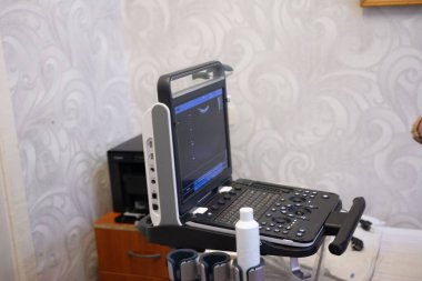 Portatif bir ultrason makinesi tıbbi bir ayarda hazır bekliyor. Makinede bir görüntü, bir klavye ve bir şişe jel gösteren bir monitör var. Tıbbi teknoloji hastalar için kullanılabilir..