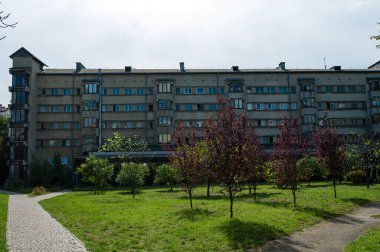 Davetkar bir mahallede, farklı bir mimari yapı canlı yeşillikler arasında duruyor, öğleden sonra güneşi altında yüzyılın ortası tasarımının özünü yakalıyor..