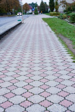 Karmaşık tasarımlarla süslenmiş büyüleyici kaldırım, huzurlu bir mahallede yemyeşil çimenler ve huzurlu bir yol kenarı ile çevrili akşam yürüyüşlerini davet ediyor..