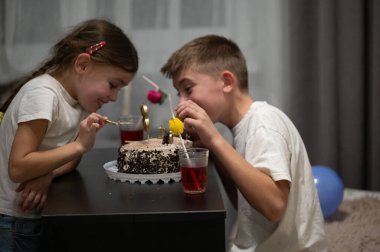 İki çocuk doğum günü kutlamasından zevk alır, renkli süslemelerle süslenmiş bir masada pasta paylaşırlar, neşe dolu bir akşamda kahkaha havayı doldurur..