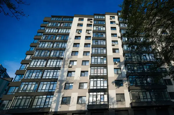 Çağdaş mimarisini ve büyük cam pencerelerini vurgulayan, canlı mavi gökyüzüne karşı belirgin bir konut yapısı, kentsel yaşama bir bakış sunuyor.