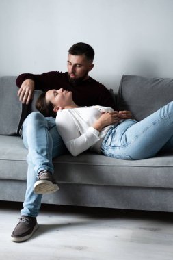 Bir çift, rahat bir kanepede sakin bir öğleden sonranın tadını çıkarıyor. Sıcak ve davetkar bir oturma odasında rahatlarken şefkat ve şefkat paylaşıyorlar..