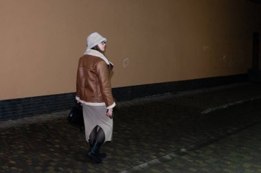Şık bir kadın gecenin bir yarısı ıssız bir caddede yürüyor, sıcak deri ceket ve rahat bir şapka giymiş, kaldırım taşlarına hafifçe dokunan botlarıyla..