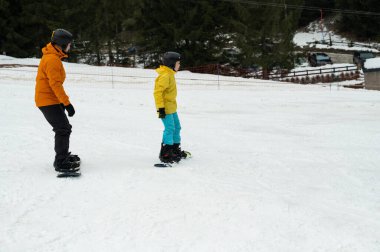 İki snowboardcu karla kaplı bir yamacı aşıp yeteneklerini ve kararlılıklarını sergiliyorlar..