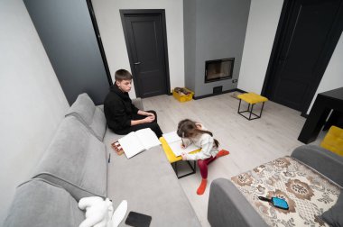 Bir kız resim yapmaya odaklanırken, bir erkek masada oturur. Etrafı sıcaklık ve yaratıcılıkla dolu şık ve davetkar bir yaşam alanıyla çevrilidir..