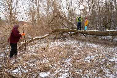 Bir grup arkadaş, karlı bir arazide kış keşiflerinin keyfini çıkarırken, bir kişi devrilmiş bir ağaçta dengede duruyor..