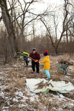 Serin bir kış gününde, insanlar açık hava ortamında birlikte çalışırlar, verimsiz ağaçların arasında yakacak odun toplarlar, işbirliği ve toplumun ruhunu gösterirler..