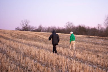Alacakaranlık çökerken, iki insan sakin bir kış tarlasında dolaşıp çıplak ağaçlarla ve serin, canlı bir atmosferle doğanın dingin güzelliğini takdir ediyor..