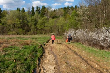 İki arkadaş parlak güneş ışığı altında çamurlu bir yolda yürüyor. Çiçek açan bitkilerin ve yemyeşil çimlerin tadını çıkarıyorlar. Huzurlu bir bahar öğleden sonrasında..