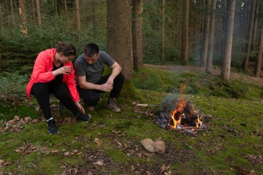 İki arkadaş, bereketli bir ormanın içindeki kamp ateşinin yanında dinleniyor. Gecenin erken saatlerinde hikayelerini paylaşıyor ve doğayla uyum içinde sıcak içecekler yudumluyorlar..