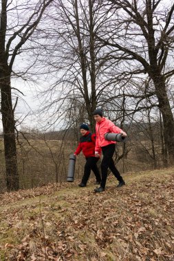 Arkadaşlar, serin kış aylarında doğanın güzelliğini keşfederken, rahat ceketlere sarılmış, yoga minderleri taşıyan huzurlu bir parkta dolaşırlar..