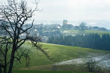 Huzurlu bir köy, yemyeşil ve karlı yamaçlarla çevrili, hafif eğimli yamaçlara dayanır..