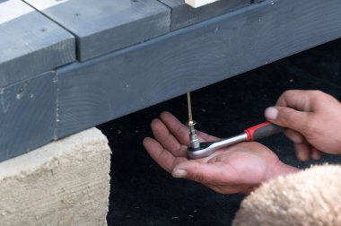 Bir adam zemini çerçeveye bağlamak için manuel olarak çardağa vida takar, iş kurulumla ilgilidir..