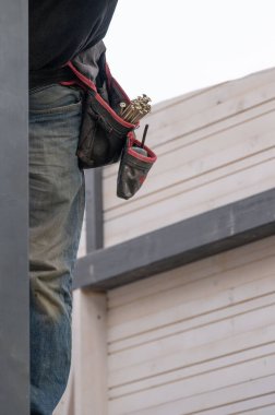 İşçinin belinde marangozluk aletleri için cepleri olan bir kemer, bir marangoz için elverişli bir iş ekipmanı..