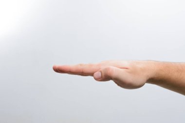 Bir erkek eli açılır, avuç içi açık ve yüzü aşağıya dönük, basit, açık gri bir arka plana karşı. Görüntü elin jestine odaklanır, sunuma, sunuma veya sunuma odaklanır..