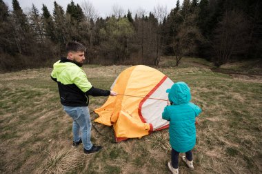 Bir baba çocuğuna ağaçlarla çevrili yemyeşil bir alanda nasıl canlı bir çadır kurulacağını öğretir. Huzurlu bir ortamda doğayla iç içe geçen neşeli bir anı paylaşıyorlar..