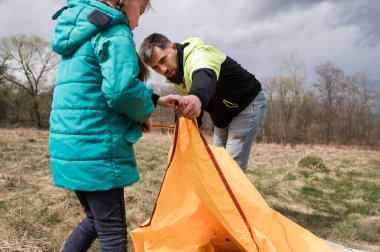 Güzel bir bahar manzarasında, bir baba ve kız birlikte çalışır, üstlerinde kara bulutlar belirdikçe turuncu bir çadır kurarlar. Heyecanları aşikar..