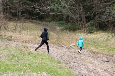 Bir çocuk ve bir yetişkin, serin bir hava için giyinmiş, sakin bir ormanda çamurlu bir yolda yol alırlar. Yeşillik ve ağaçlar keşfettikçe huzurlu bir atmosfer yaratıyor..