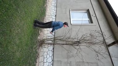 Tarafsız bir duvara karşı çıplak bir dalın yanında duran bir adam, doğa ve mimari arasındaki zıtlığı sessiz bir anda vurguluyor..