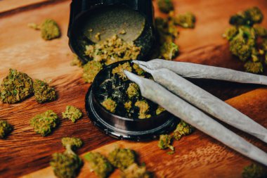 Öğütücü yakın çekim, çimenler ve koniler, uyuşturucular ahşap bir masanın üzerinde.