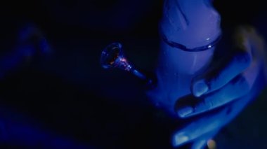 Erkek eli marihuanayla nargileyi tıkar. Uyuşturucu ve uyuşturucu bağımlısı. Adam ot içiyor. Neon mavi ışık. CBD veya THC